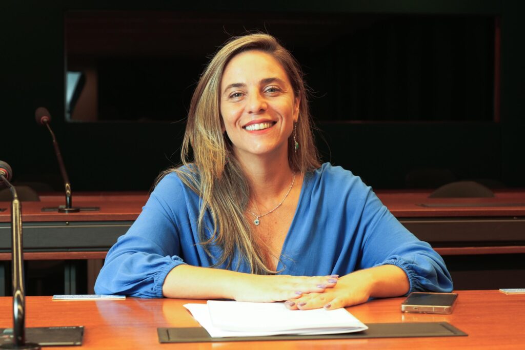 Fernanda Melchionna sorrindo, sentada à mesa de uma comissão